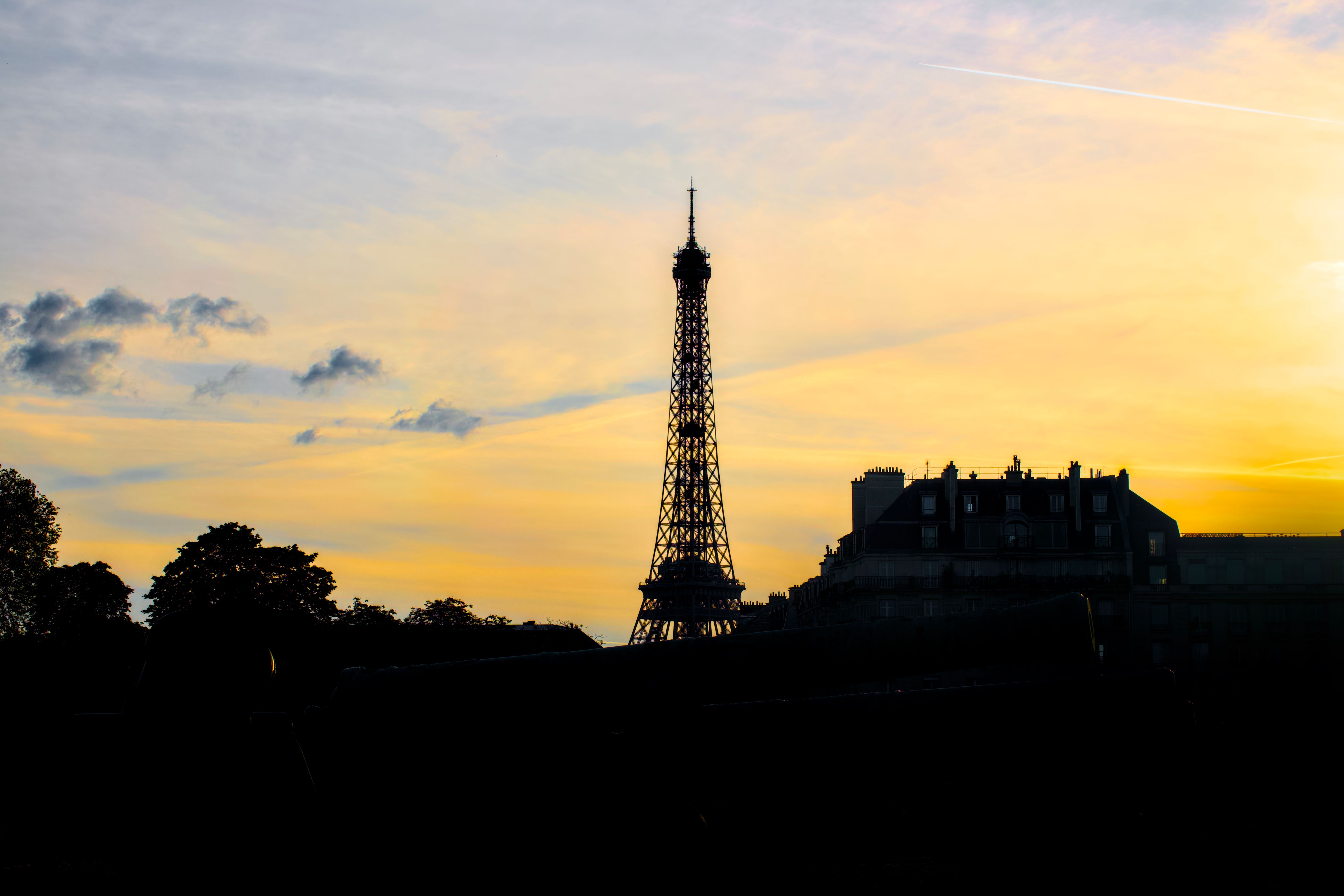 La silhouette de la tour Eiffel sous un ciel doré au coucher du soleil, à Paris